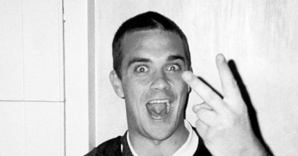 Image in QuizMyDay Feel the Trivia – How Much Robbie Is in Your Playlist? trivia quiz featuring Example of photographs included in Henry Bond's 2000 photo-book "Point and Shoot" the photograph depicts Singer/entertainer Robbie Williams using a "V sign" hand gesture to the photographer.