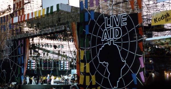 Image in QuizMyDay Aid Your Memory: The Ultimate Live Aid 1985 Quiz trivia quiz featuring Jimmy Page, Robert Plant, and John Paul Jones on stage with drummers Tony Thompson and Phil Collins in addtion to bassist Paul Martinez performing at Live Aid at JFK Stadium, Philadelphia, 1985