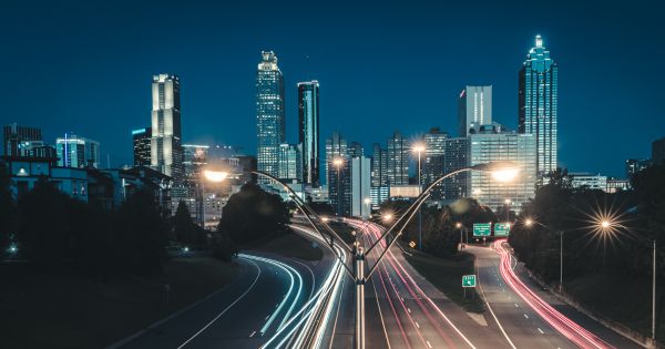 Image in QuizMyDay Hip Hop Geography Quiz: Match Rappers to Their Hometowns trivia quiz featuring An image of the Atlanta, Georgia Skyline taken at dawn with long exposure to create light trails of the morning traffic. Taken from the Jackson Street Bridge that passes over the John Lewis Freedom Parkway.