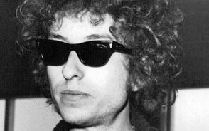 <i><a href="https://sv.wikipedia.org/wiki/Bob_Dylan" class="extiw" title="sv:Bob Dylan">Bob Dylan</a> kom till Arlanda på onsdagseftermiddagen. Här ses han med en av sina medmusikanter.</i><br>Ett av de dyraste artistbesöken i Sverige har inletts: på onsdagseftermiddagen kom den världsberömda amerikanska sångaren Bob Dylan till Arlanda. På fredag ger han konsert i <a href="https://sv.wikipedia.org/wiki/Stockholms_konserthus" class="extiw" title="sv:Stockholms konserthus">Stockholms konserthus</a> inför en publik som betalt upp till 40 kronor för att få se honom. Dylan har på förhand meddelat att han vill vara i fred på onsdagen, så de pressmän som fanns på plats på Arlanda fick uppleva en ovanligt trumpen och surmulet tyst idol, omgiven av bortemot tjugotalet livvakter och medhjälpare. På torsdagen har emellertid de svenska arrangörerna fått nådigt tillstånd att anordna en presskonferens med Dylan.