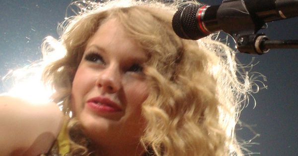 Image in QuizMyDay Taylor Swift Early Years Quiz – Test Your Music Memory trivia quiz featuring Country pop singer Taylor Swift performs "Fifteen" on the Fearless Tour in 2010, wearing a yellow dress.