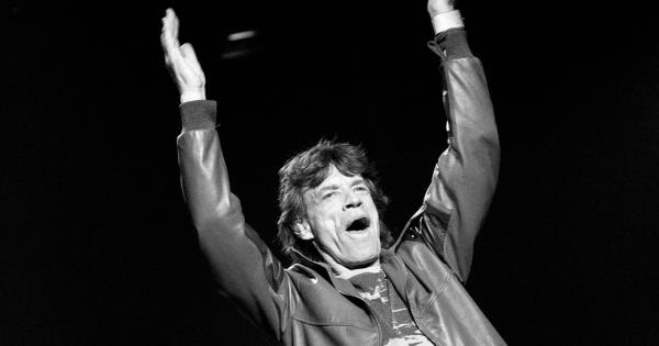 Image in QuizMyDay Rolling Stones Trivia Quiz: How Well Do You Know the Legendary Band? trivia quiz featuring Mick Jagger waving his hands up in a black and white photo.